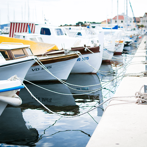 Various boats tied up to the pier at a marina.